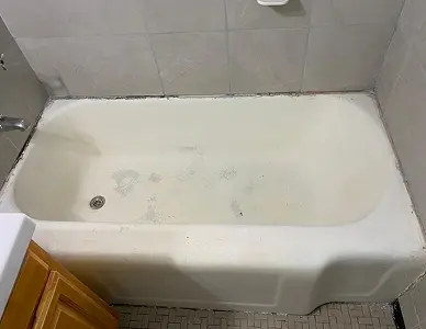 Bathtub before restoration with chipped, faded coating